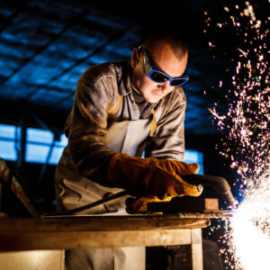 Worker cutting metal with plasma equipment on plant.